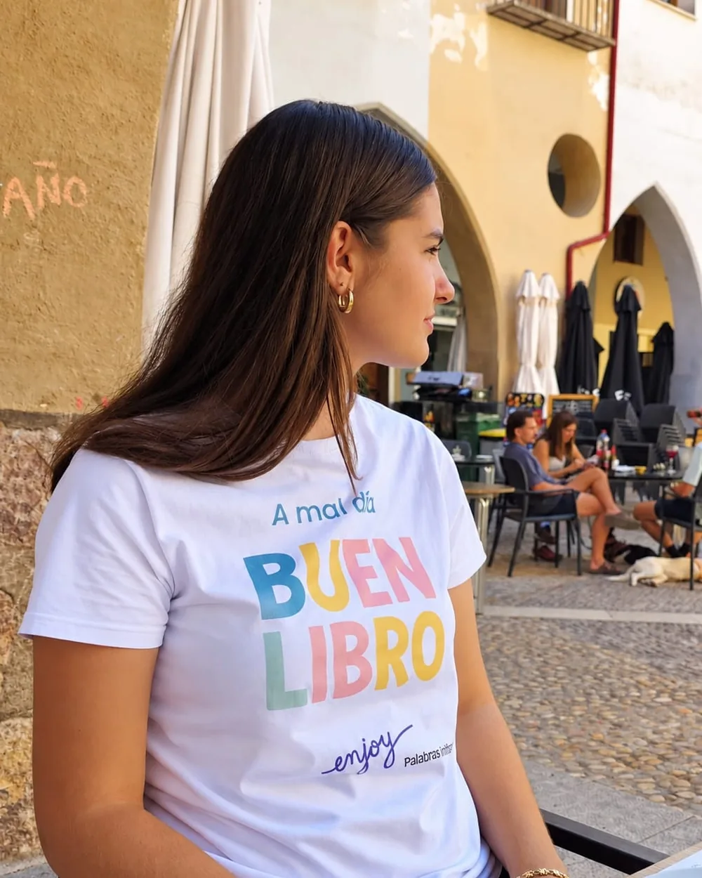 Chica con la camiseta A mal día, buen libro de Colorins en una plaza